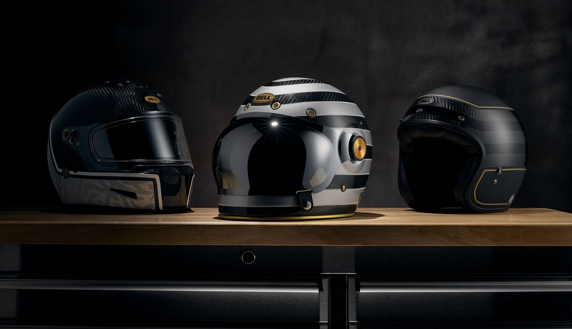 Three motorcycle helmets on a wooden surface with a dark background