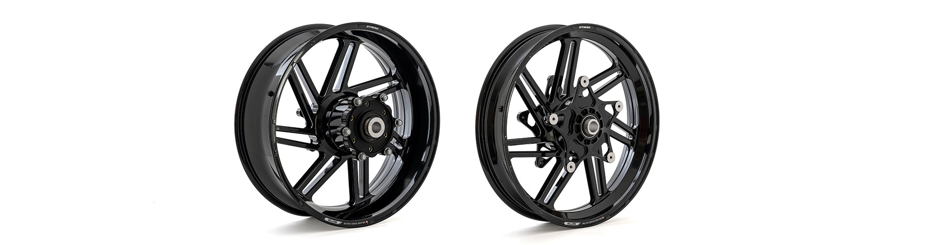 Two sleek black Dymag racing wheels side by side against a white background. Both wheels feature intricate spoke designs with a shiny finish, labeled 'Dymag UP7X' and equipped with central hubs for high-performance racing applications.