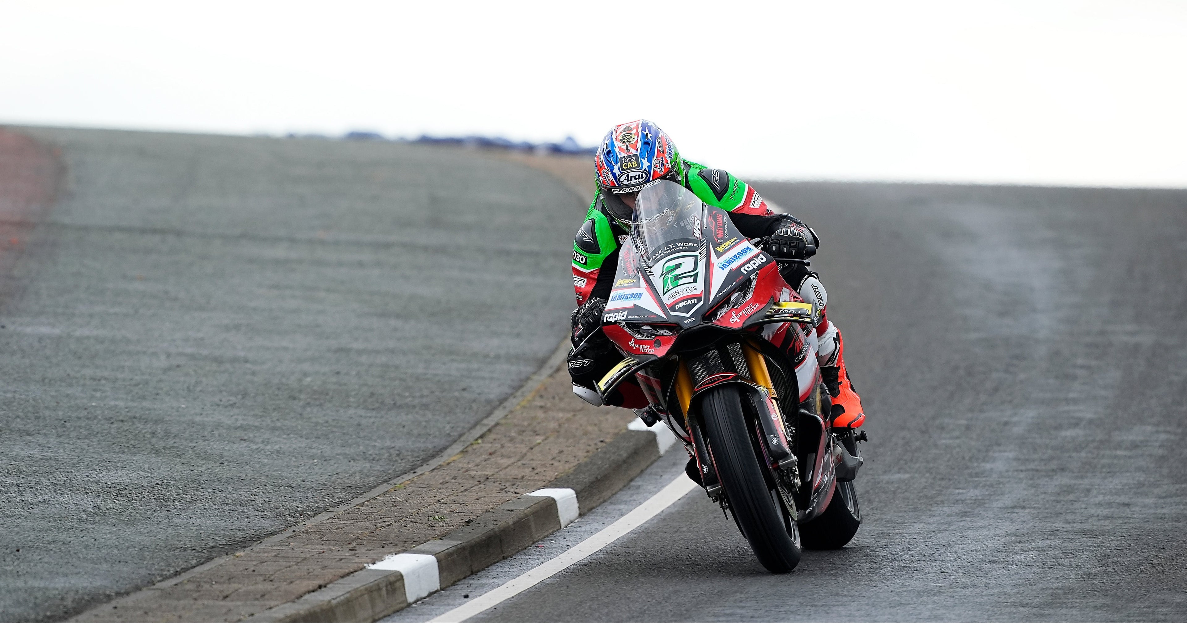 Motorcyclist on a race track wearing a helmet and racing suit.
