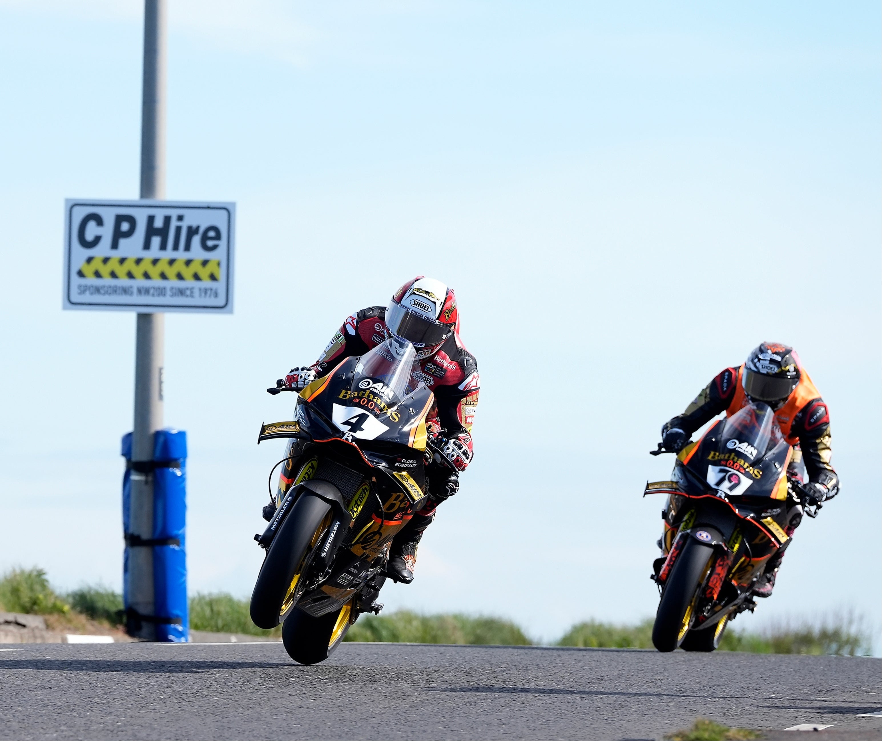 Two motorcyclists racing on a track with a 'CP Hire' sign in the background.