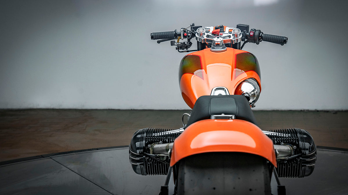 rear photo of the orange RSD x BMW R18 Dragster II motorcycle. Good view of the hand controls and riders view